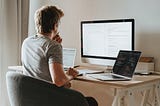 A man sits thoughtfully at his computer