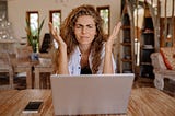 A frustrated woman sits at a desk in front of a computer