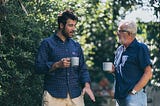 old father and son having morning coffee in a garden