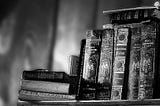 A greyscale picture of a few old books on a shelf — signifying wisdom.