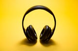 Black over ear headphones on yellow background