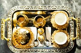 An ornate tray of gold and silver crockery to denote a luxurious life