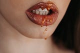 A woman’s mouth dripping with honey.