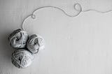 Three grey yarn balls on a light grey background