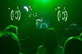An electronic music festival, with a DJ on stage in the distance