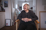 Margaret Calvert seated and smiling in her London studio
