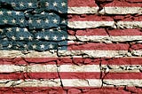 Ain’t that America: A splintered and shattered image of the American flag, symbolizing the state of the United States today.