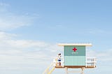 A man stands atop an elevated structure that appears to be a Red Cross stand