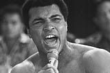 Muhammed Ali shouting into a microphone in his hand