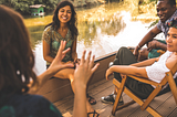 People sitting on a dock by a river, sharing stories