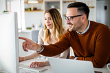 Professionals in business casual attire look at a desktop.