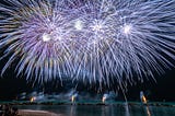 A brilliant blue fireworks display over water.