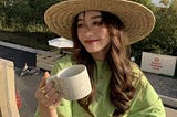a girl holding a tea cup and worn hat