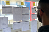 Person looking at some wireframes hanged on a large window.