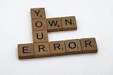 Wooden blocks that say “Own Your Error”