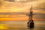 An old sailing ship floats on calm waters