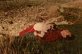 A photo of the author as a child, lying on top of her Dad, in the grass.