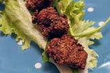 Photo by author. Three pieces of boneless fried chicken sit on a lettuce leaf on a blue plate.