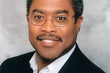 Photo of a smiling middle aged man in a shite shirt and jacket.