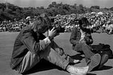 Two men sitting looking through their cameras.