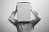 A man with a box on his head because he feels invisible