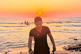The author walking by a sunset at a beach.