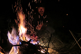Man sitting at a beautiful campfire with an empty chair next to him