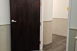 A tall automatically closing fire door propped open at an apartment