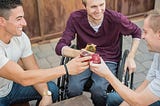 Man, on a wheelchair, enjoying his drink with friends.