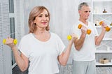 Over 50 man and woman exercising with weights.