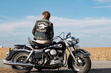 Austin Butler wearing Vandals jacket sitting on motorcycle