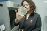 Sarah Richardson, CEO of MicroByre, holds up a petrie dish with bacterial cultures for the camera.