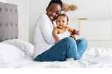 Getty Images. Photo showing cheerful black mother hugging her baby.