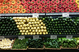 Rows of vegetables sit on shelves in the produce section of a grocery store.