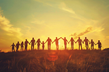 a group of people holding hands, looking at the sunset