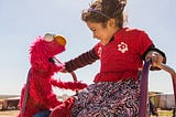 A young girl plays with Elmo