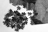 Partially completed puzzle with scattered pieces on a white background, symbolizing a product being designed without a clear vision.