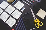 Um smartphone, post-its, canetas e lápis — ferramentas para prototipagem rápida de um designer.