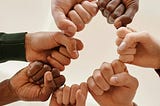 A circle of seven fists, all different skin tones (sharing power with each other)