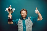 Smiling man holding a trophy and giving the thumbs up.