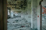 Photograph of a crumbling cement building with damage and multicolored graffiti painting on the walls.