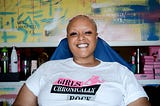 Keisha, smiling, wearing a Girls Chronically Rock white shirt and gold skirt.
