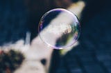 A large single bubble in the foreground of a picture with a blurred background