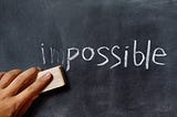 The word impossible written on a chalkboard with an eraser removing the first two letters.