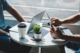 Two people with laptops working in a coffee shop.