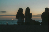 three women watching the sunset by the water, the third slightly out of frame