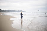 A young woman walking on the beach, and watching birds flying away