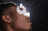 A Black man has paper butterflies over his eyes.