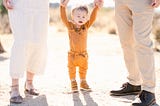 Toddler supported by parents’ hands in desert