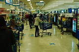 Customers wait in lines at grocery store during COVID-19 pandemic.